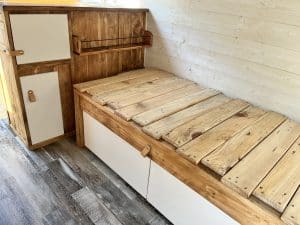 Lit en bois dans un van aménagé